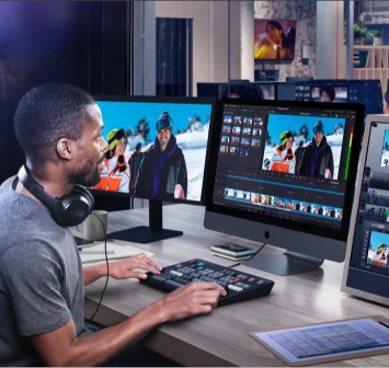 Video editor viewing footage on two monitors in an editing room